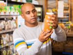Man reading jar contents on label while shopping in supermarket