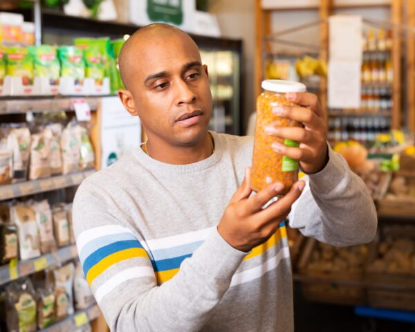 Man reading jar contents on label while shopping in supermarket