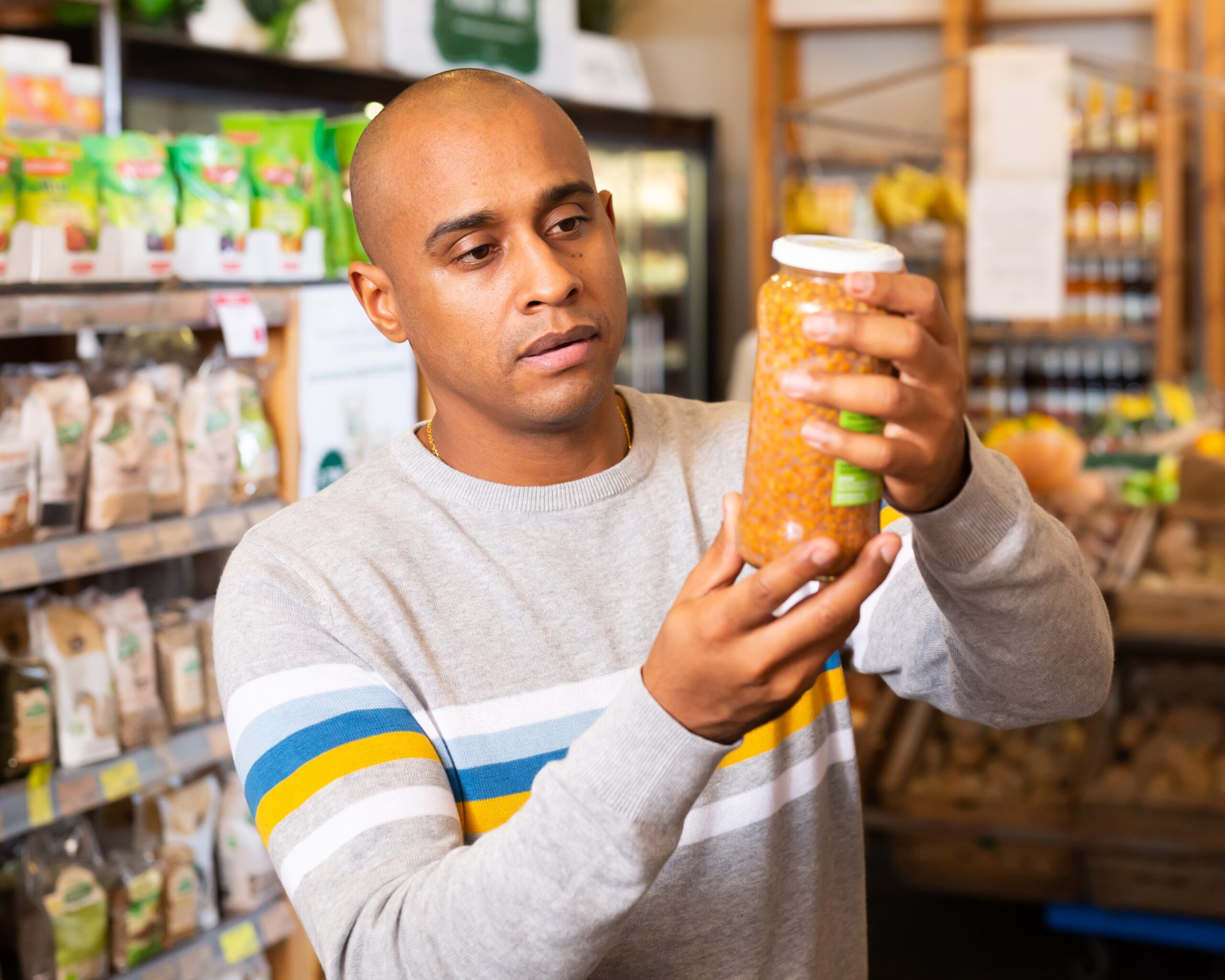 Man reading jar contents on label while shopping in supermarket