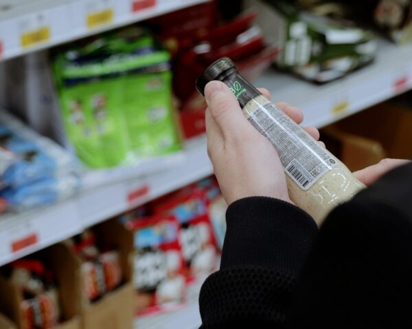 A customer in black studies the label on a bottle of sauce.